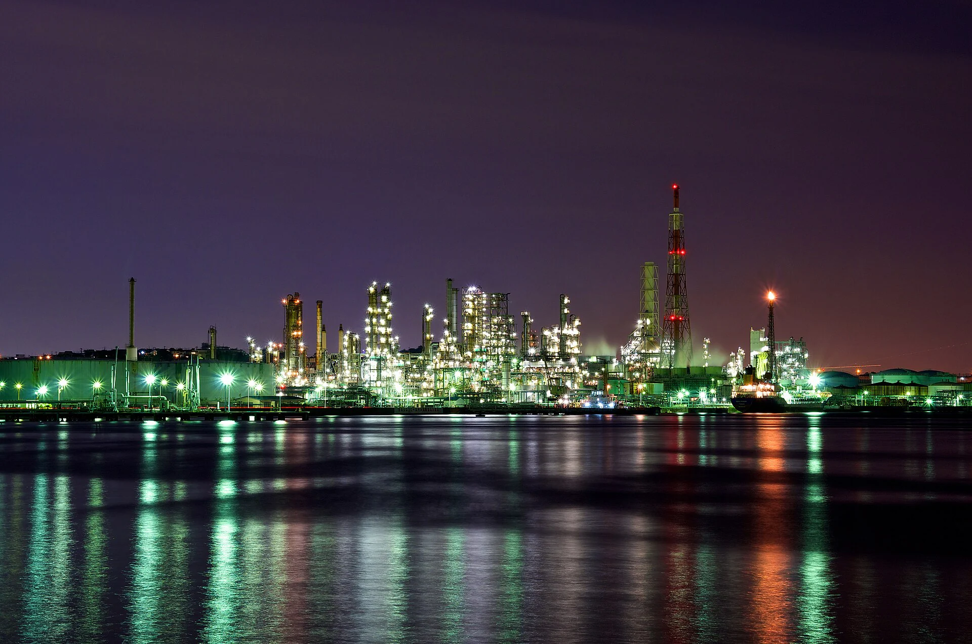 Illuminated refinery towers and industrial piping at night
